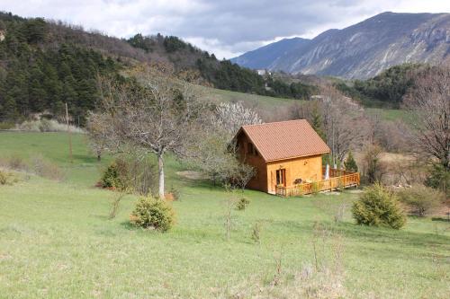 a small wooden house in a field with mountains in the background at Le Chalet du Berger in Briançonnet
