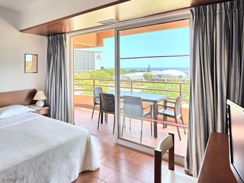 a bedroom with a bed and a balcony with a table and chairs at Dom Pedro Portobelo in Vilamoura