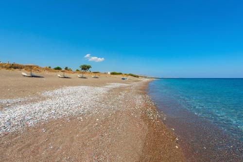 a beach with some chairs and the ocean at Horizon Line Villas in Kiotari