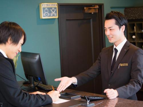 two men sitting at a desk in front of a computer at Hotel AreaOne Nobeoka in Nobeoka