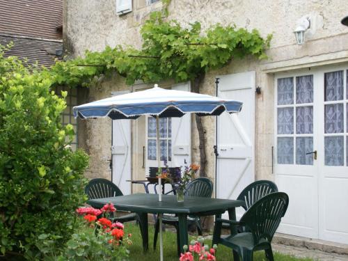 a table and chairs under an umbrella in a yard at Beautiful holiday home near the forest in Labastide-Murat