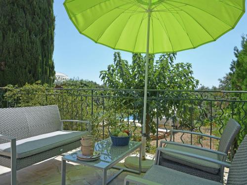 a patio with a green umbrella and a table and chairs at Spacious holiday home with private pool in Saint-Maximin