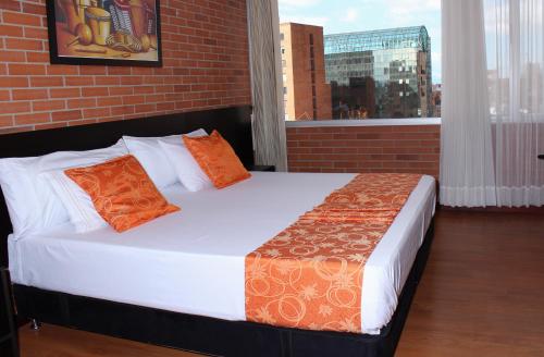 a bed with orange pillows in a room with a brick wall at Hotel Bogota Astral in Bogotá
