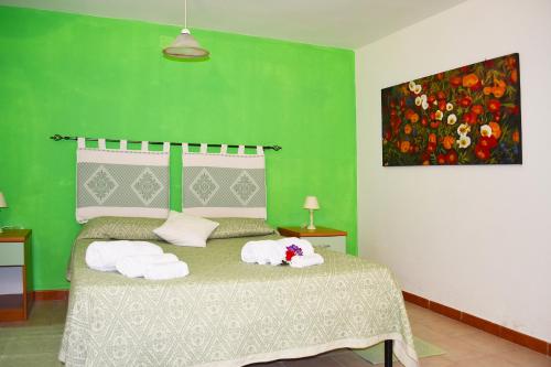Un dormitorio verde con una cama con toallas. en Casa Vacanza Porto Frailis già Porto Frailis B&B en Àrbatax
