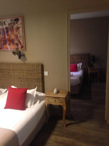 a bedroom with a bed with red pillows and a table at Hotel Cote Patio in Nîmes