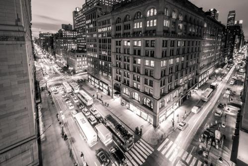 a black and white photo of a city street with traffic at U Hotel Fifth Avenue, Empire State Building in New York