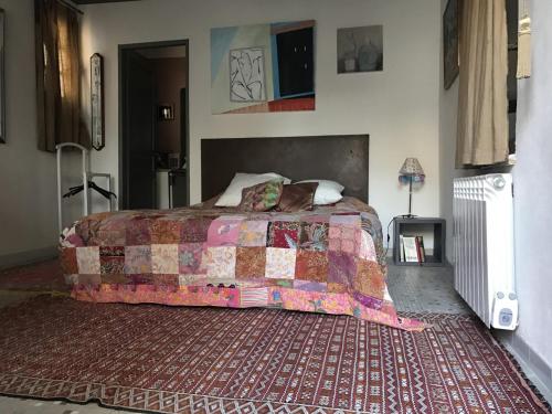 een slaapkamer met een bed en een tapijt bij Nid d'Artiste in Saint-Quentin-la-Poterie