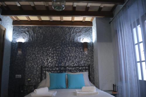 a bedroom with a bed with blue pillows and a wall at Casa Mirador San Pedro in Arcos de la Frontera