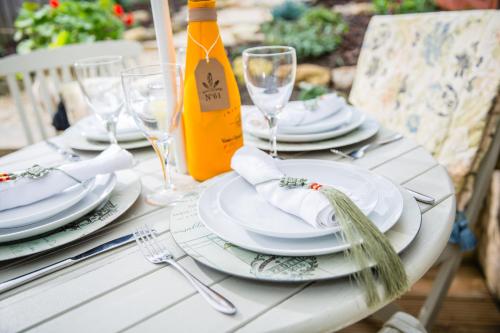 a white table with plates and glasses and a bottle of wine at No61 Winchcombe (Cotswolds) in Winchcombe