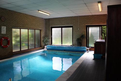 a large swimming pool in a room with windows at B&B The Pippins in Sandy
