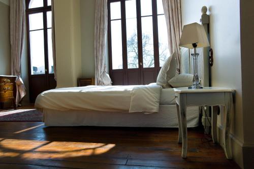 a bedroom with a bed and a table and windows at Hostellerie du Coq d'Or in Jonzac