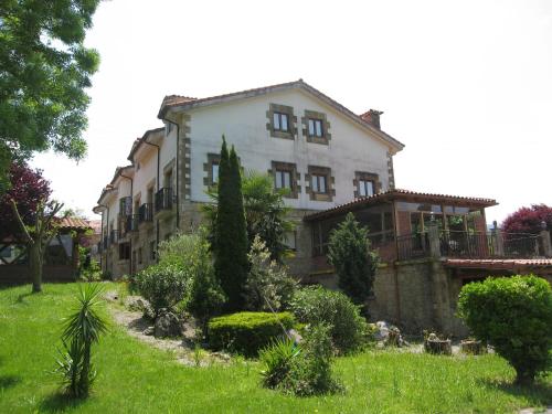 a large white building with trees in a yard at Posada La Anjana in Puente Viesgo