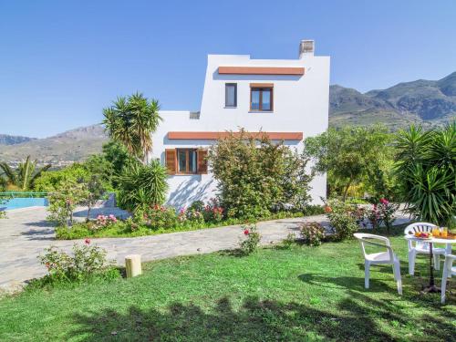 LefkogeiaにあるChic Villa in Lefkogia Crete with Swimming Poolの庭付きの家(テーブルと椅子付)