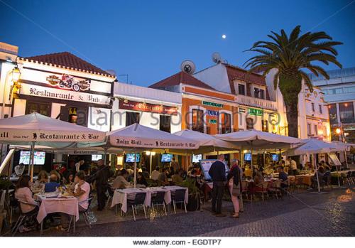 a group of people sitting at tables in front of buildings at Torre Mar Apartment in Cascais