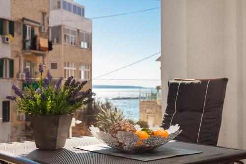 a table with a bowl of fruit and a vase of flowers at Bepo Luxury Apartments in Split
