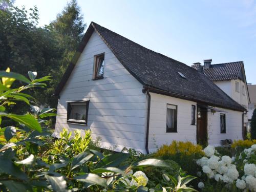 uma pequena casa branca com um telhado preto em Holiday home in Ramsbeck with garden em Ramsbeck