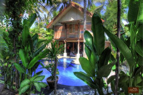 a house in the jungle with a pool in front of it at Villas SAMALAMA Gili Trawangan in Gili Trawangan