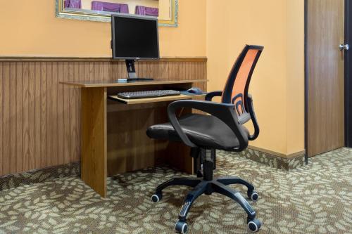a desk with a computer monitor and a chair at Super 8 by Wyndham Antigo in Antigo