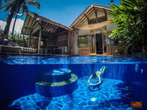 a woman is in the water in a swimming pool at Villas SAMALAMA Gili Air in Gili Air
