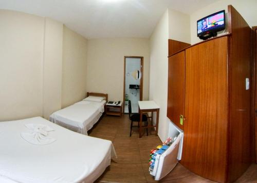 a hotel room with two beds and a flat screen tv at QualyLeste Hotel in Caratinga