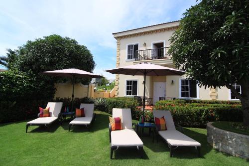 a group of chairs and umbrellas in front of a house at Star View Boutique Resort in Dumaguete