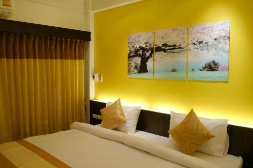 a bedroom with a bed with two paintings on the wall at Lertnimit Hotel in Chaiyaphum