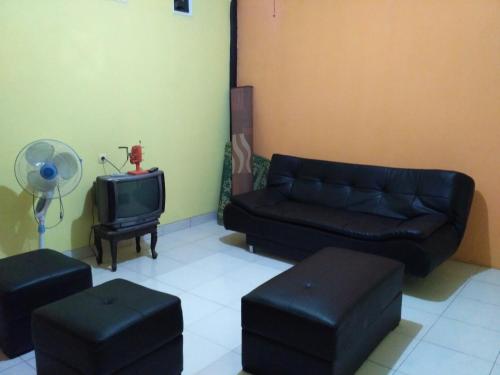 sala de estar con sofá y TV en mas Eko Jlatren kost homestay en Prambanan