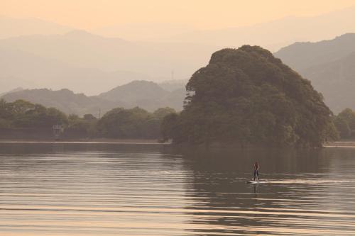 a person on a paddle board in a body of water at PavilionSurf&Lodge in Shishikui