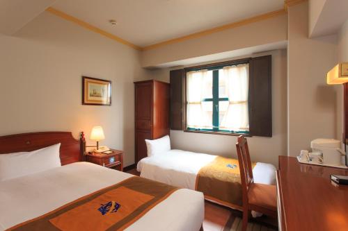 a hotel room with two beds and a cross on the window at Hotel Monterey Nagasaki in Nagasaki