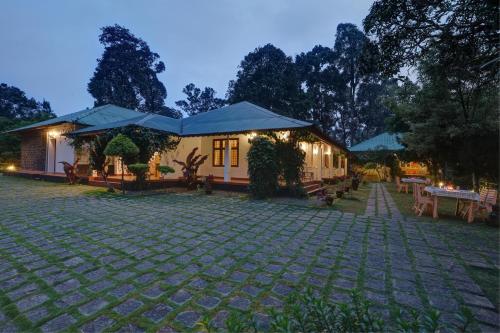 a house with a cobblestone courtyard in front of it at Dew Drops Farm Resorts in Munnar
