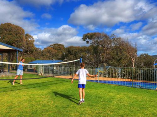 two children playing soccer on a tennis court at Beach Cabins Merimbula in Merimbula