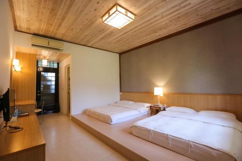 a bedroom with two beds and a television in it at Tobacco Village in Meinong