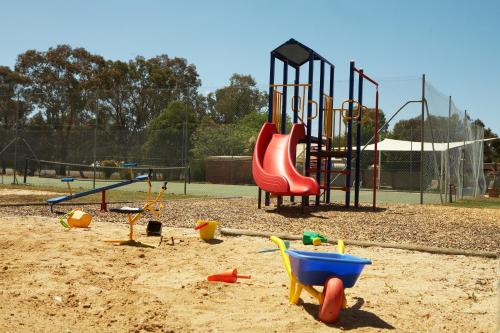 un parque infantil con un tobogán rojo en la arena en Cadell On The Murray Motel en Moama