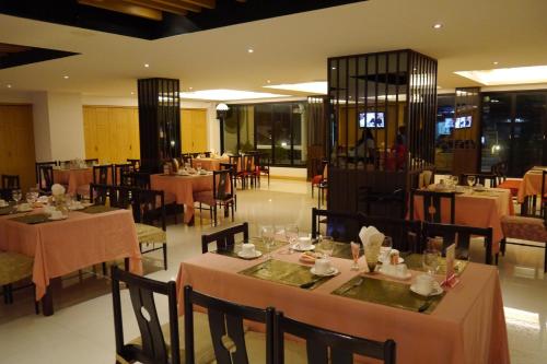 uma sala de jantar com mesas e cadeiras e mesa de cabeceira em Lertnimit Hotel em Chaiyaphum