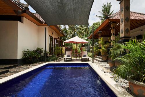 a pool with two chairs and an umbrella in front of a house at Villa Jackson in Tejakula