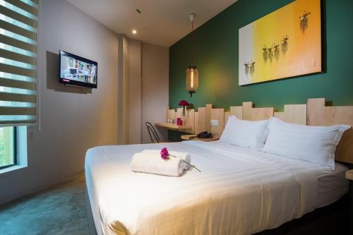 a bedroom with a large white bed with a green wall at Finess Basic Hotel in Malacca