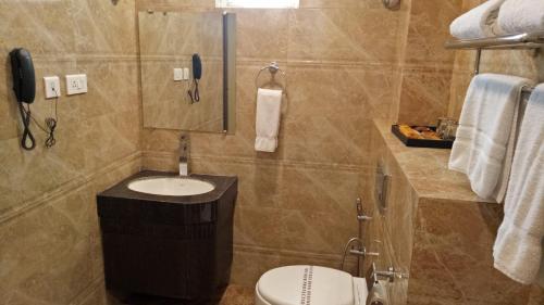 a bathroom with a toilet and a sink and a phone at Hotel Patliputra Continental in Patna