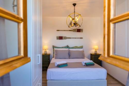 a bedroom with a bed with two windows and a chandelier at Lindos SeaView Apartment in Líndos