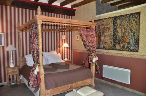 a bedroom with a canopy bed and a painting on the wall at La Tour du Lion in Rochefort-en-Terre