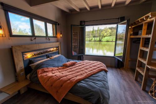1 dormitorio con 1 cama, chimenea y ventana en LACabane Lodge Nature, en Saint-Vivien