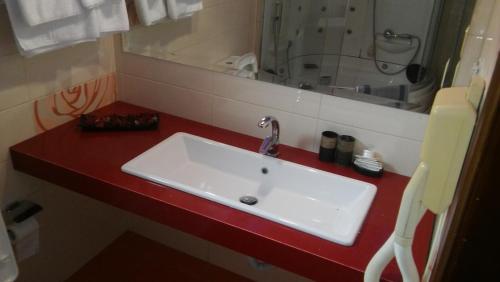 La salle de bains est pourvue d'un lavabo blanc sur un comptoir rouge. dans l'établissement Nefeli Hotel, à Kozani