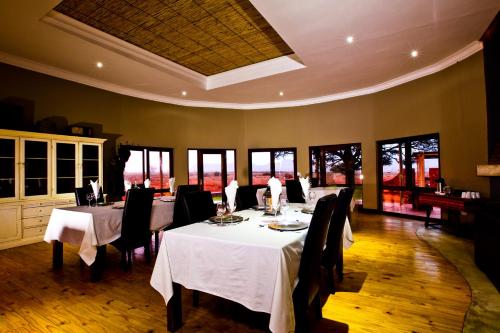 a dining room with tables and chairs and windows at We Kebi Safari Lodge in Sesriem
