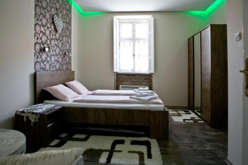 1 dormitorio con 1 cama con luz verde en Gyulai 200 Éves Apartman, en Gyula
