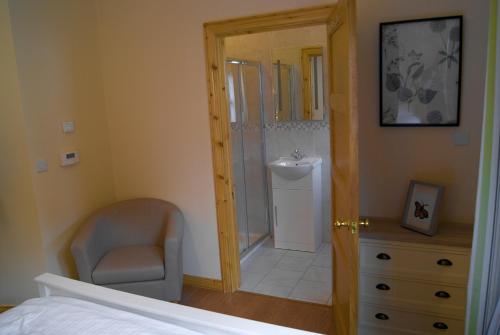 1 dormitorio con 1 cama y 1 silla y baño en Old School House Belcoo 41, en Belcoo