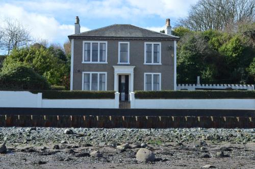 a house with a white fence and a gravel yard at Briar Brae Bed & Breakfast in Stranraer