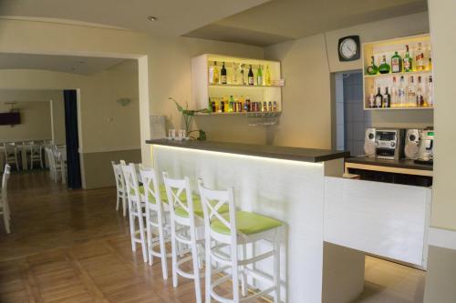 a bar with a row of white stools at Hotel Merkur in Miercurea-Ciuc