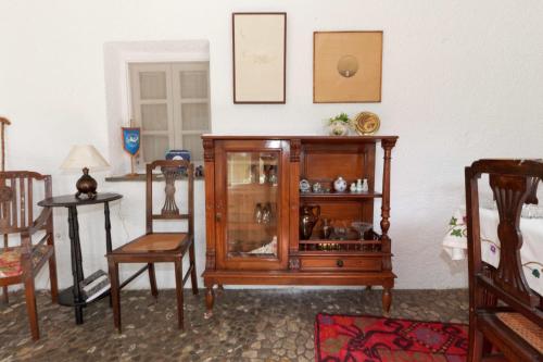 a living room with a wooden cabinet and chairs at To Spitaki Apartments in Galaxidhion