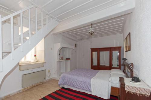 a white bedroom with a bed and a staircase at To Spitaki Apartments in Galaxidhion