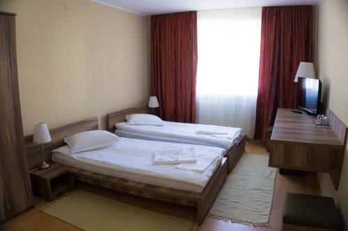 a hotel room with two beds and a television at Hotel Merkur in Miercurea-Ciuc