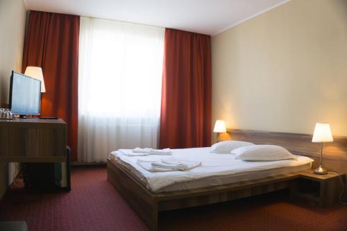 a bedroom with a bed and a large window at Hotel Merkur in Miercurea-Ciuc